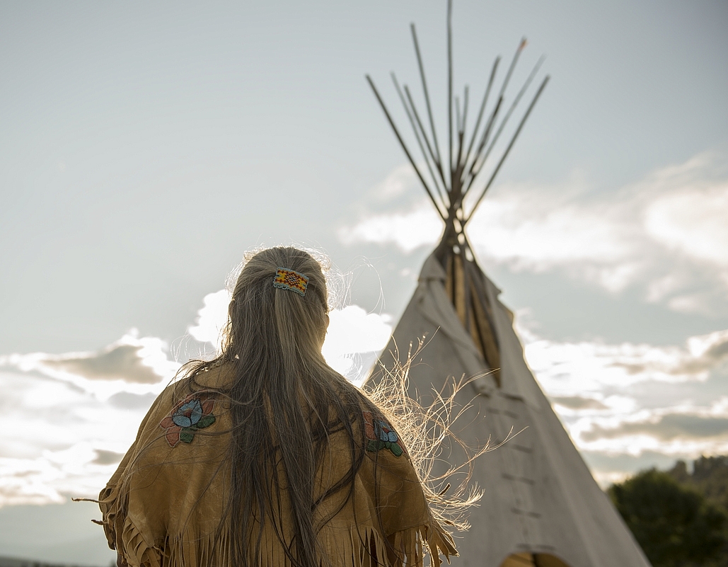 Ktunaxa elder in regalia next to a teepee at St Eugene Golf Resort