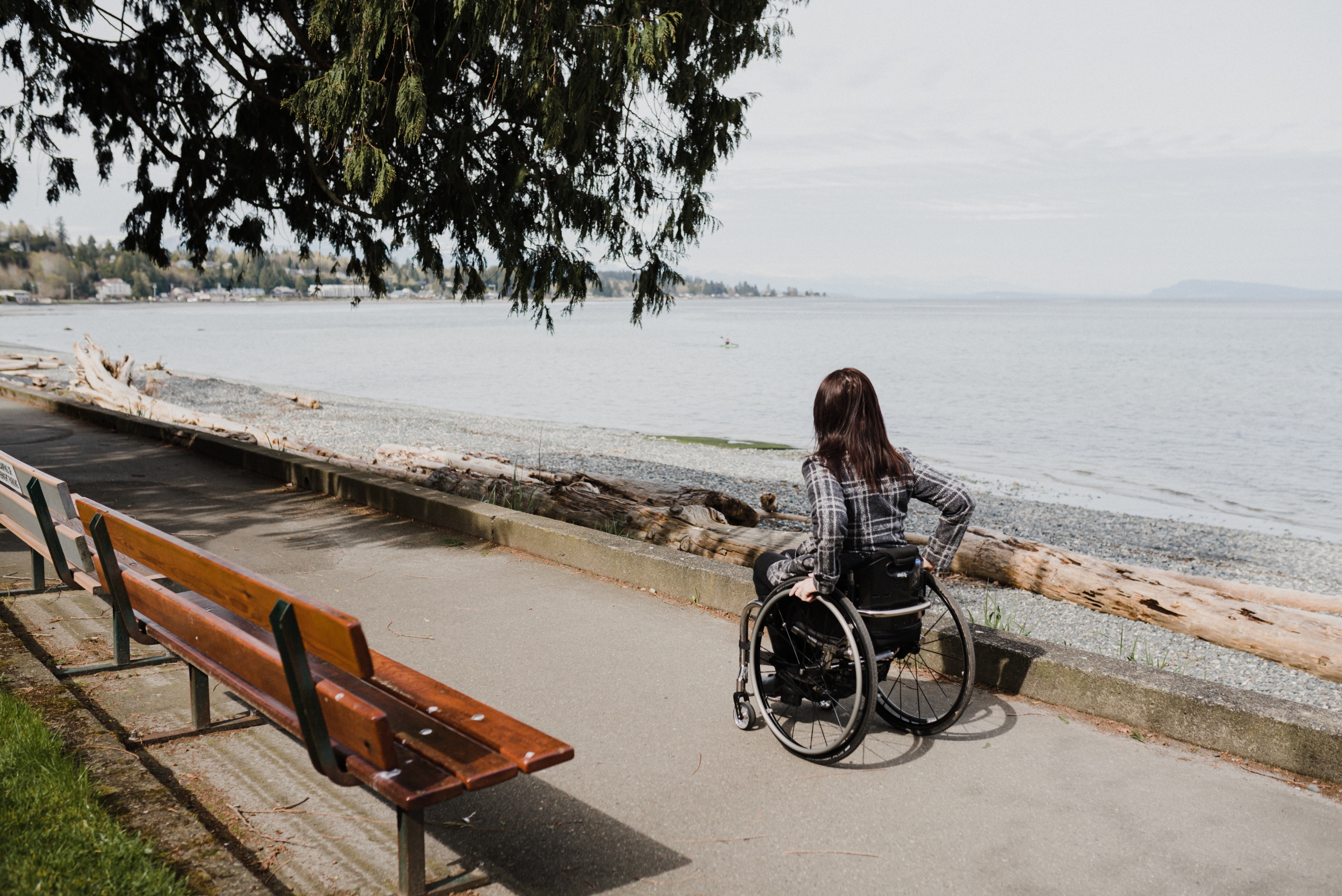 Woman in a wheelchair on a paved path along the Qualicum Beach waterfront | Lexa Bergen